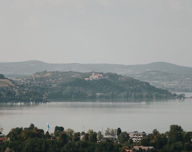 A town on the far shore of a lake under a pale sky